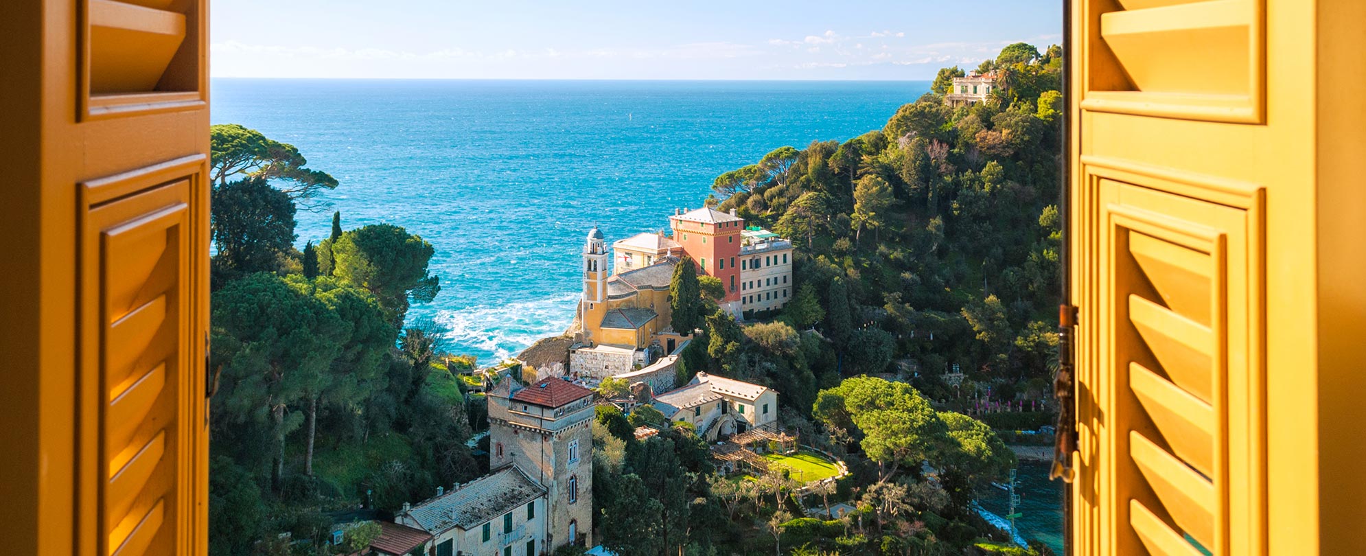An open window overlooking the sea and town of Portofino, Italy on the Italian Riviera coastline.